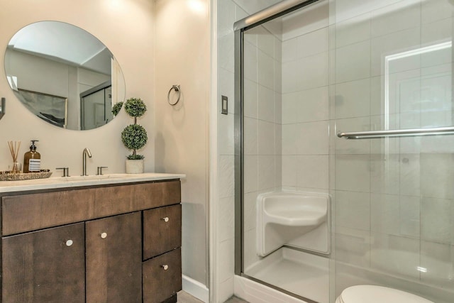 bathroom with toilet, a stall shower, and vanity