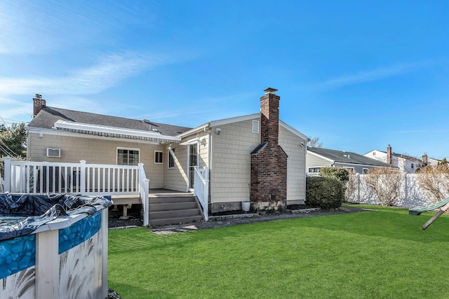 exterior space featuring a wooden deck, a yard, fence, and a chimney