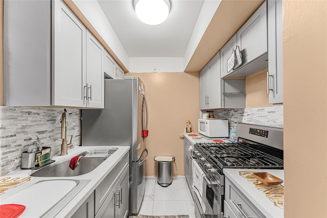 kitchen featuring white microwave, a sink, light countertops, marble finish floor, and stainless steel gas stove