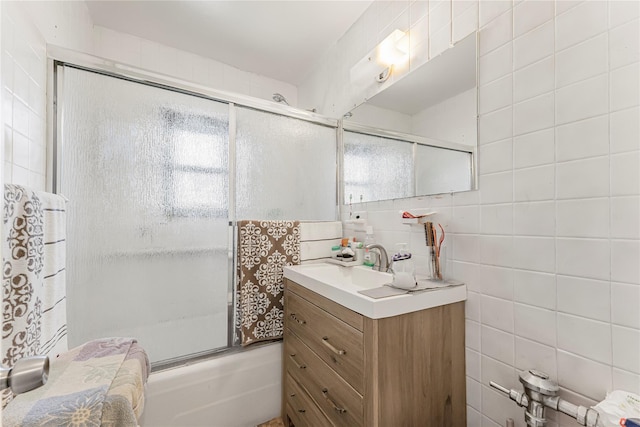 full bath with decorative backsplash, shower / bath combination with glass door, tile walls, and vanity