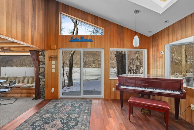 foyer featuring vaulted ceiling with skylight, wooden walls, and wood finished floors