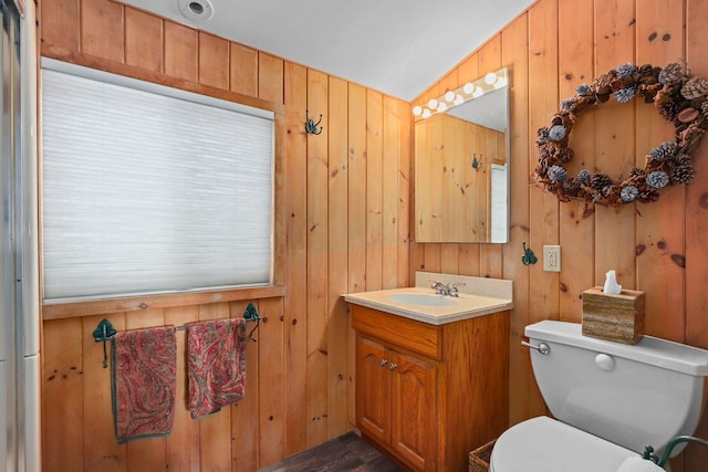 bathroom with vanity, toilet, wooden walls, and vaulted ceiling