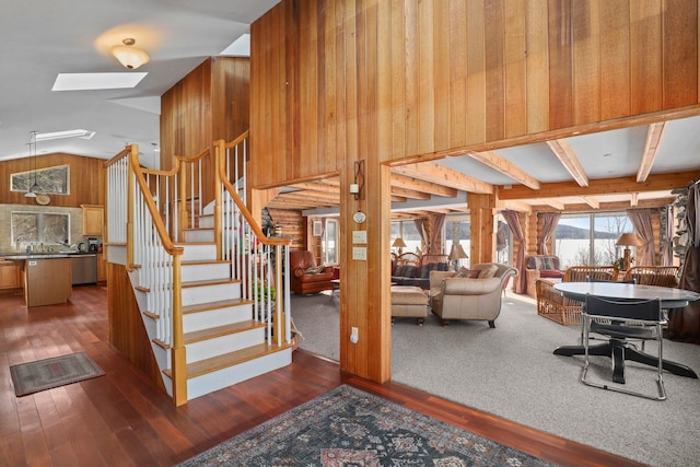 stairway with wood-type flooring, wood walls, and lofted ceiling with skylight