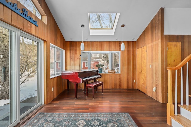 interior space with a healthy amount of sunlight, a skylight, wood walls, wood finished floors, and stairs