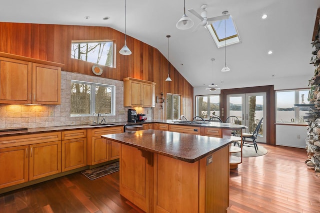 kitchen featuring a skylight, a center island, a sink, high vaulted ceiling, and a peninsula