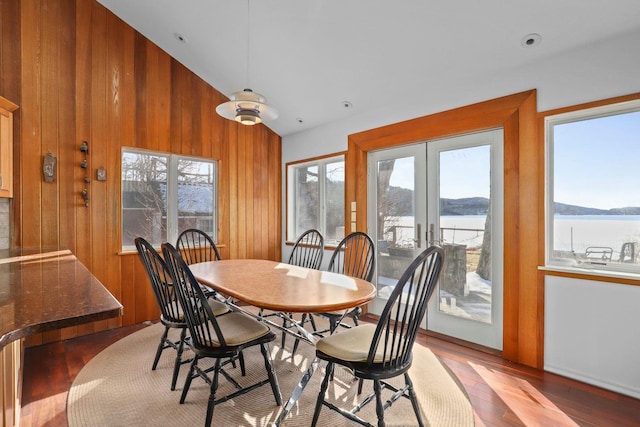 dining space featuring french doors, wood walls, high vaulted ceiling, a mountain view, and light wood-style flooring