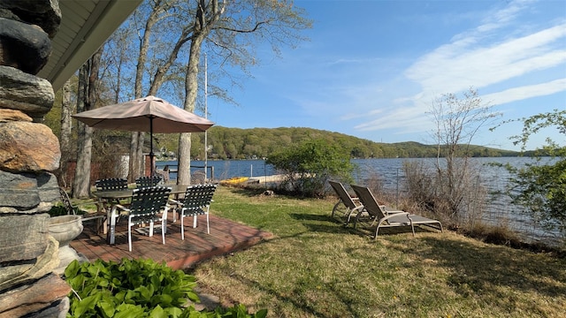 view of yard with a deck with water view and outdoor dining space