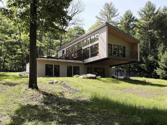 back of house with stucco siding, a yard, and a wooden deck