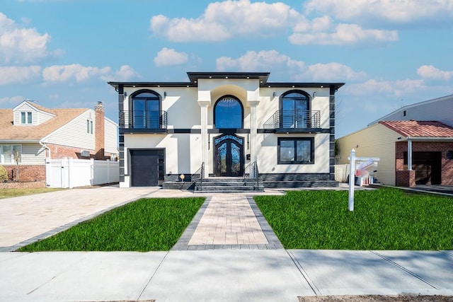 view of front of property with stucco siding, a gate, decorative driveway, fence, and a balcony