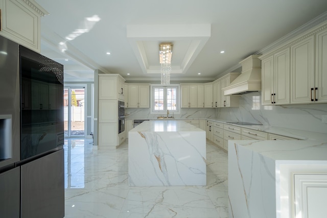 kitchen featuring premium range hood, black appliances, light stone counters, a tray ceiling, and a sink