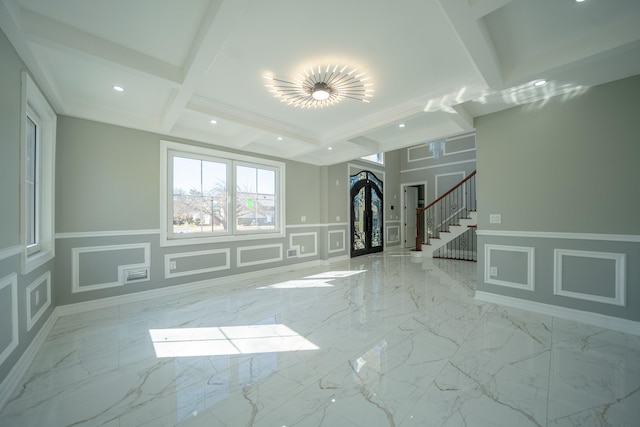 unfurnished living room with a decorative wall, marble finish floor, stairs, and beamed ceiling