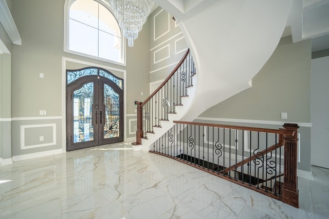 entryway featuring stairway, french doors, a towering ceiling, a notable chandelier, and marble finish floor