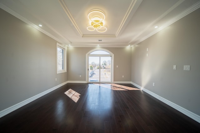 empty room with crown molding, baseboards, a raised ceiling, and dark wood-type flooring