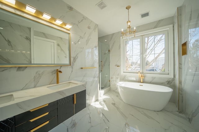 bathroom with visible vents, marble finish floor, a freestanding bath, and stone wall