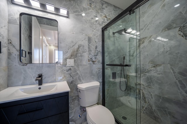 bathroom with a marble finish shower, toilet, vanity, and tile walls