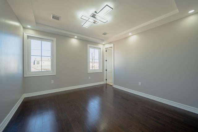 spare room featuring recessed lighting, baseboards, dark wood-type flooring, and a raised ceiling