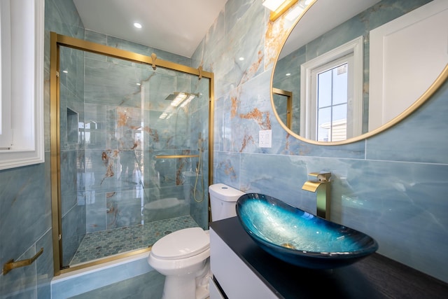 bathroom with vanity, toilet, tile walls, and a shower stall