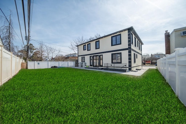 rear view of house with a fenced backyard, stucco siding, a patio, and a yard