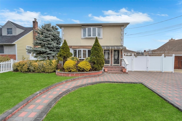 view of front of home with a gate, stucco siding, a front lawn, and fence