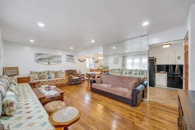 living room featuring light wood finished floors, a notable chandelier, recessed lighting, and an AC wall unit