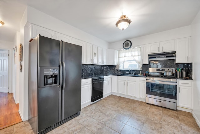 kitchen with dark countertops, tasteful backsplash, under cabinet range hood, black appliances, and a sink