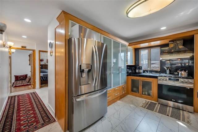 kitchen with dark countertops, glass insert cabinets, custom range hood, appliances with stainless steel finishes, and marble finish floor