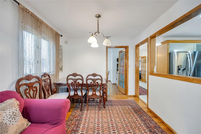 dining area with an inviting chandelier, wood finished floors, and french doors