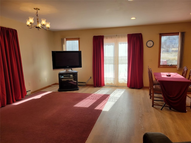 living room featuring baseboards, light wood-style floors, a healthy amount of sunlight, and a chandelier