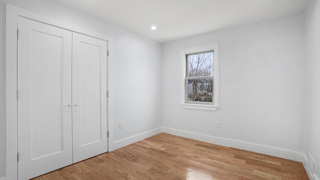 unfurnished bedroom featuring light wood finished floors, visible vents, baseboards, recessed lighting, and a closet