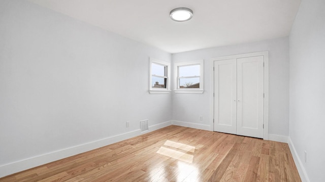 unfurnished bedroom featuring light wood finished floors, visible vents, a closet, and baseboards