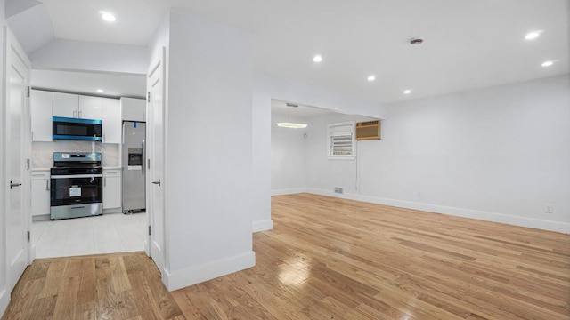 interior space with a wall mounted air conditioner, light wood-type flooring, and recessed lighting