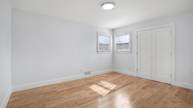 unfurnished bedroom with visible vents, baseboards, a closet, and wood finished floors