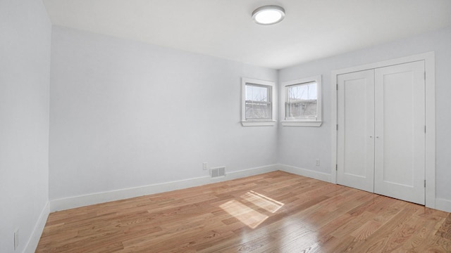 unfurnished bedroom with visible vents, baseboards, a closet, and light wood-style flooring