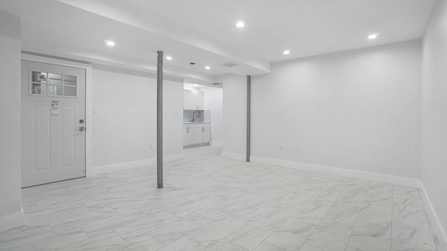 finished basement with visible vents, baseboards, recessed lighting, marble finish floor, and a sink