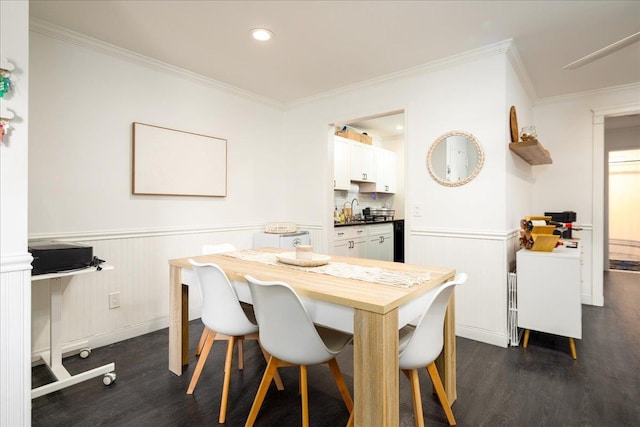 dining space featuring wainscoting, dark wood-type flooring, and ornamental molding