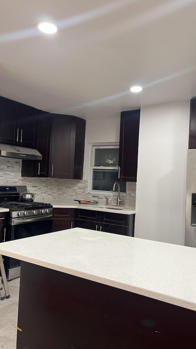 kitchen featuring recessed lighting, appliances with stainless steel finishes, under cabinet range hood, a sink, and backsplash