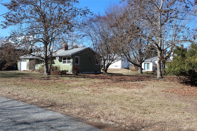 exterior space with a yard, a chimney, and an attached garage