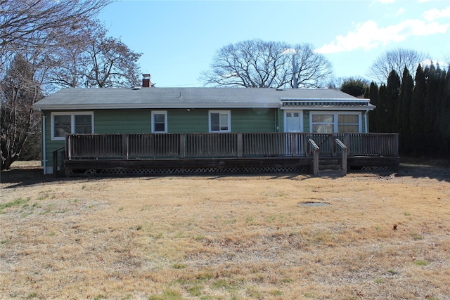 view of front of home with a chimney, a wooden deck, and a front yard