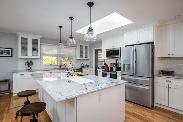 kitchen featuring a skylight, white cabinets, and stainless steel appliances