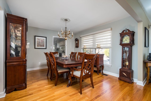 dining room featuring visible vents, baseboards, light wood-type flooring, and a chandelier