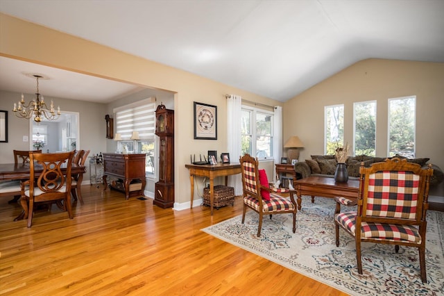 living room with baseboards, lofted ceiling, an inviting chandelier, and light wood-style flooring