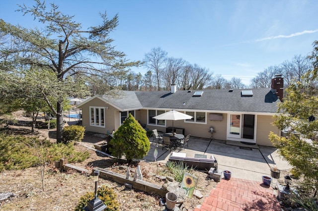 back of property featuring a patio area, a chimney, and a shingled roof