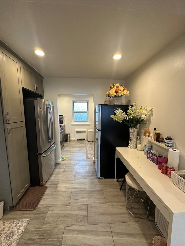 kitchen with light countertops, radiator heating unit, recessed lighting, and freestanding refrigerator