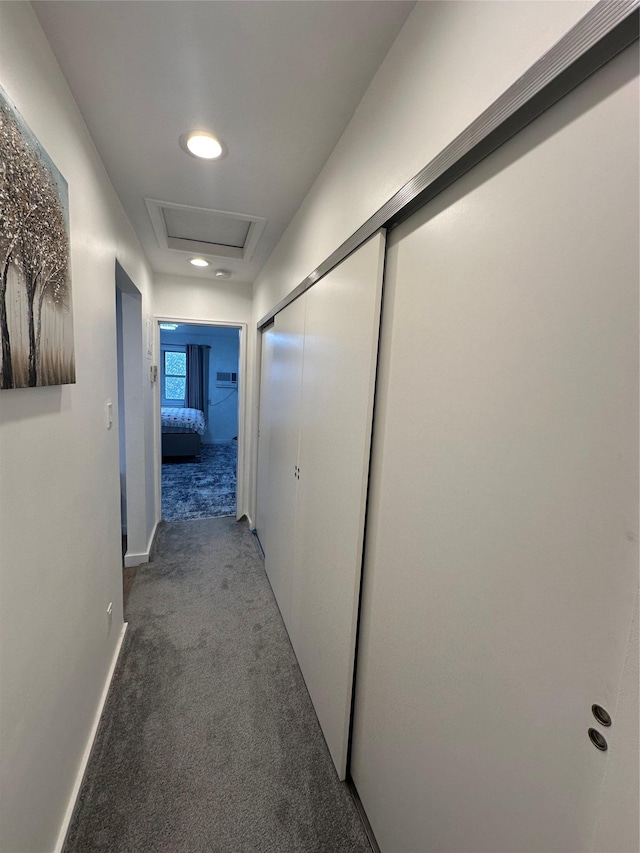 hallway with carpet flooring, attic access, and baseboards