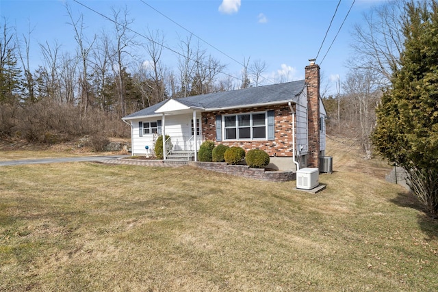 view of front of home with central AC unit, a chimney, a front yard, and roof with shingles