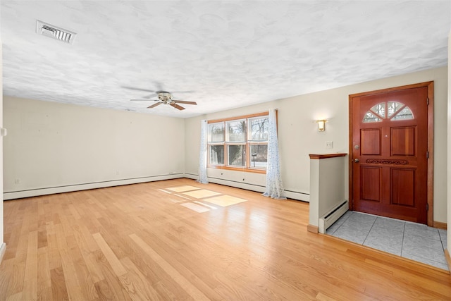 entryway with visible vents, a textured ceiling, wood finished floors, and a baseboard radiator