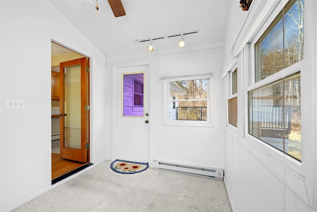 unfurnished sunroom featuring baseboard heating, rail lighting, ceiling fan, and a baseboard radiator