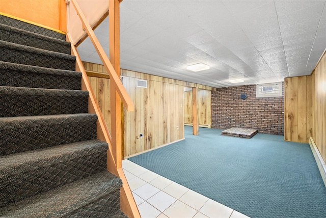 finished below grade area with visible vents, wooden walls, carpet flooring, and stairs