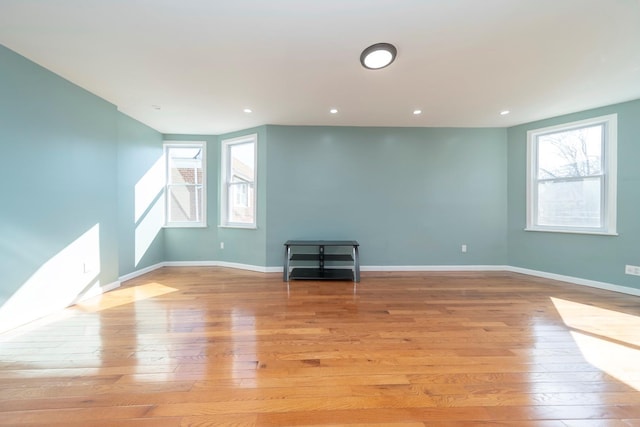 unfurnished living room featuring baseboards, light wood-style floors, and a healthy amount of sunlight