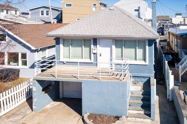 bungalow with a garage, roof with shingles, and driveway